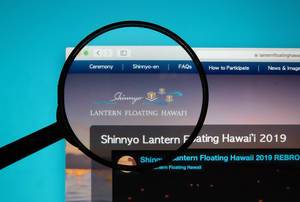 Internetseite des Lantern Floating Hawaii auf Computerbildschirm mit Lupe über Logo