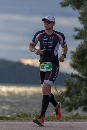 Ironman-Teilnehmer aus Finnland, beendet den Triathlon erfolgreich nach der Marathonstrecke in Lahti, mit dem Vesijärvi-See im Hintergrund