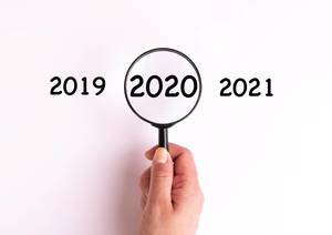 Jahreszahl 2020 auf weißer Oberfläche unter einer Lupe dargestellt