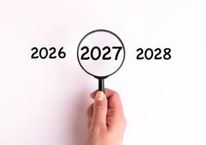 Jahreszahl 2027 auf weißer Oberfläche unter einer Lupe dargestellt