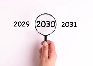 Jahreszahl 2030 auf weißer Oberfläche unter einer Lupe dargestellt