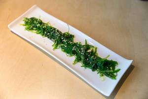 Japanische vegane Beilage zum Essen "Goma Wakame" -  ein Salat aus essbaren Algen und Sesam, auf einem Holztisch