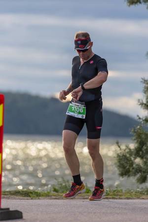 Jogger guckt auf die Uhr während er den Halbmarathon des Ironman-Wettkampfs an der Küste von Lahti läuft