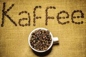 Kaffeetasse voll von Kaffeebohnen und Kaffee geschrieben im Hintergrund