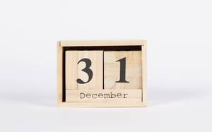 Kalender in Holzkiste zeigt Silvestertag 31. Dezember vor weißem Hintergrund
