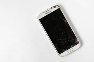 Kaputtes Smartphone mit gesprungenem, zebrochenem Display auf weißem Hintergrund, mit Platz für eigenen Text