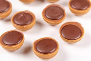 Karamell-Schokoladen Pralinen mit Haselnuss auf weißem Hintergrund Nahaufnahme