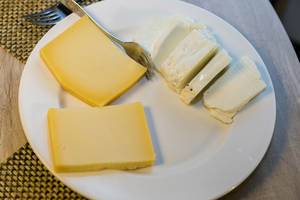 Käsescheiben für Raclette und Weichkäse auf Teller auf Holztisch