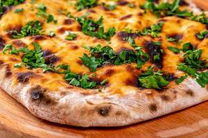 Khachapuri with cheese and herbs on wooden kitchen Board