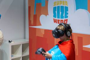 Kind im Superhelden-Kostüm spielt mit VR-Brille