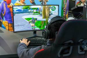 Kind spielt das Computerspiel Fortnite auf einem Nvidia Curved-Monitore