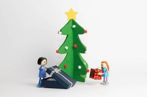 Kinder öffnen ihre Weihnachtsgeschenke, Holzfiguren mit einem Weihnachtsbaum