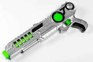 Kinderspielzeug-Pistole in grau und grün auf weißem Untergrund