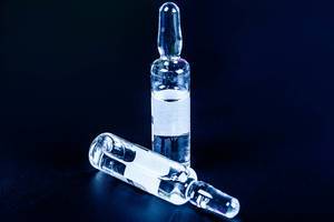 Kleine Glasampullen mit flüssigem Arzneimittel auf schwarzem Hintergrund