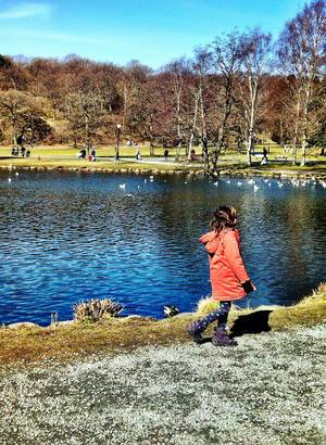 Kleines Mädchen spaziert entlang eines Teichs im Park
