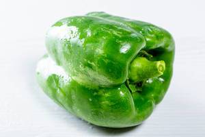 Knackige, mit Tautropfen überzogene grüne Paprika isoliert vor weißem Hintergrund