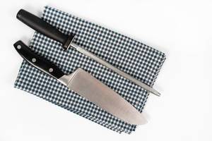 Knife and Knife Sharpener on the kitchen dishcloth on the white background (Flip 2020)
