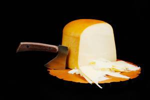 Knife cutting slices of sheep cheese, black background
