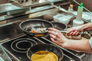 Koch bereitet Omelette mit Schinken zu