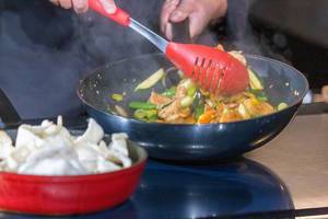 Koch kocht eine asiatische Gemüsepfanne mit Garnelen und Krabbenchips