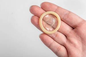 Kondom ohne Verpackung auf der Hand eines Mannes