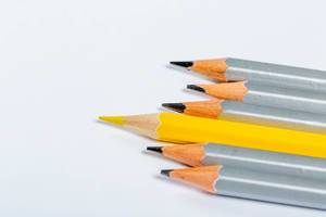 Konzept: Führung - unkonventionell denken für den Geschäftserfolg - alles graue Stifte und ein gelber, der herausragt, auf weißem Hintergrund