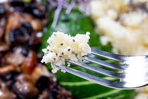 Konzept gesunde Ernährung: Nahaufnahme von Couscous mit Chiasamen auf einer Gabel