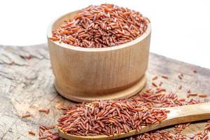 Konzept gesunde Ernährung: Roher brauner Vollkorn-Reis in einer Holzschale