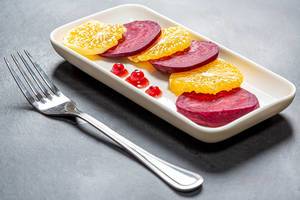 Konzeptbild gesunde Küche: Salat mit Orangen und Rüben, mit Beerensauce und roten Korinthen