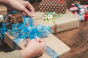 Konzeptbild "Weihnachtsvorbereitungen": Mädchen bindet eine Schleife um das Weihnachtsgeschenk