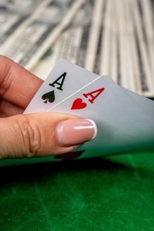 Konzeptbild zum Thema Glücksspiel um Geld, zeigt ein Pokerspiel mit Spielkarten in einer Frauenhand