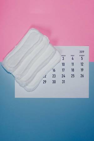 Konzeptbild zum Thema Menstruationszyklus, zeigt Damenbinden auf einem Kalender, aus der Sicht von oben