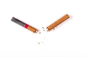 Konzeptbild zum Thema "Mit dem Rauchen aufhören" zeigt eine durchgebrochene Zigarette mit Tabakkrümmel auf weißem Untergrund
