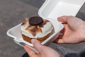Kronut - Snack by "chök" pastry shop in a to-go packaging, glazed with white chocolate and an oreo cookie, in Barcelona, Spain