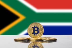 Kryptowährung Bitcoin in Gold vor der Staatsflagge von Südafrika