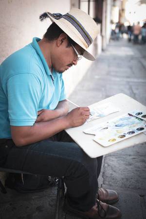 Künstler mit Zeichnungsmappe sitzt in einer Straße und malt