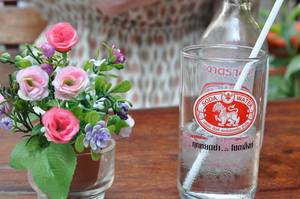 Künstliche Blumen und ein Glas Sodawasser mit Strohhalm