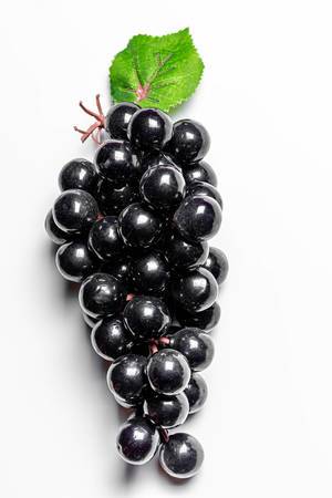 Künstliche schwarze Weintrauben auf weißem Hintergrund Draufsicht