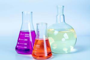 Laboratory glassware with colored liquids on light background
