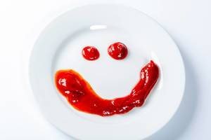 Lachendes Gesicht mit Ketchup auf Teller gezeichnet vor weißem Hintergrund