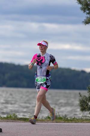 Läuferin rennt die 21,097 km Marathonstrecke am Seeufer in Lahti, Finnland, um den Ironman 70.3 erfolgreich zu beenden