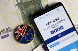 Leave.eu website on mobile phone with Brexit medal coin on Euro banknotes