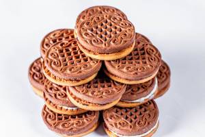 Leckere, runde Schokoladekekse mit Cremefüllung gestapelt vor weißem Hintergrund