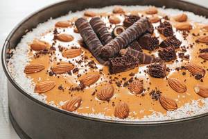 Leckerer Schokoladenkuchen mit Kokosraspeln und Mandeln dekoriert in der Kuchenform