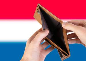 Leerer Geldbeutel aus Leder mit Flagge der Niederlande. Rezession und Finanzkrise werden mit mehr Schulden und Bundeshaushaltdefizit einhergehen