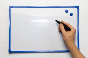 Leeres Whiteboard mit blauem Rahmen und blauen Magneten mit Hand und schwarzem Markierstift - Nahaufnahme frontal
