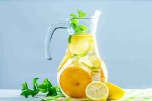 Lemonade pitcher with lemon, mint and ice on table (Flip 2019)