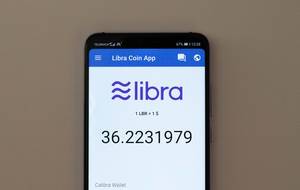 Libra Coin App auf einem Smartphone vor grauem Hintergrund