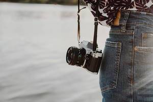 Lifestyle photo of a vintage film camera on a girl. Sea background.