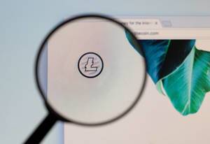 Litecoin logo on a computer screen with a magnifying glass